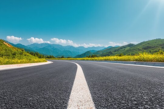 Empty asphalt road winding through a green landscape, leading towards distant mountains under a bright blue sky