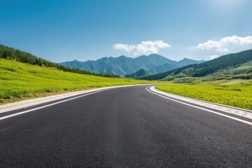 Naklejka premium Clean asphalt highway winding through a green valley with mountains and blue sky in the background on a sunny day