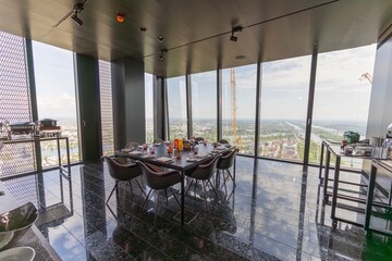 A contemporary dining area showcasing sophisticated furnishings and large panoramic windows that...
