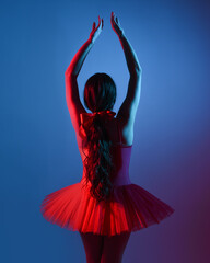 Silhouetted ballerina in red tutu and pointe shoes facing away, backlit by dramatic blue and red neon lighting, poised in elegant three-quarter pose under moody theatrical studio light © faestock