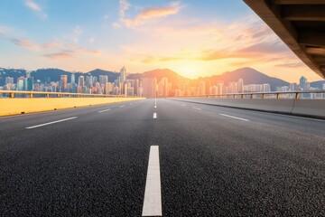 Asphalt road leading through urban Hong Kong with mountains and skyscrapers in the background at sunset