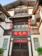 Traditional Chinese wooden building with ornate carvings, stone lions, and calligraphy signs
