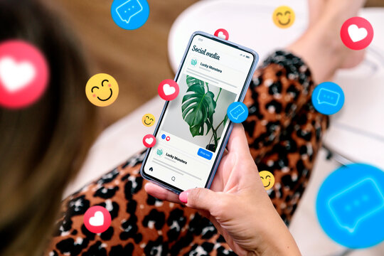 Social media ads on a mobile phone screen with emojis. A woman with a smartphone showing an example of a social media ad.