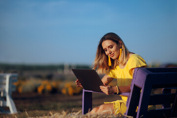 Happy Woman Working on her Laptop Outdoors in a Field. Person  typing on her notepad being...