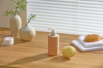 Bathroom setup with wooden surface, ceramic vases, amber bottle, towel and bath sponge. Natural...