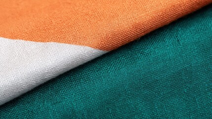 Close-up of fabric with orange, white, and green sections, showing detailed woven texture and vibrant colors.