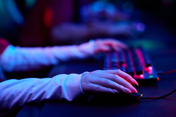 Hands of teenage girl gamers using computer keyboard and mouse during esports competition, focusing on precise movements and teamwork in gaming environment, multiethnic group participating © pressmaster