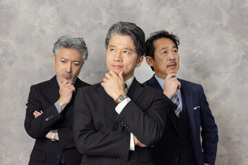 考えるミドルエイジ男性ビジネスパーソンのグループ