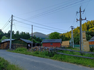 A rural road with a fence and power lines in the background