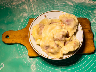 A plate of dumplings on a wooden cutting board on a table