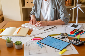 Architect working on a project for a sustainable building, using a computer and eco-friendly...