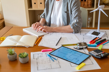 Architect working on a sustainable building project. Using a computer and reviewing blueprints....