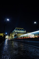 Flat vector is showing illuminated theatre with cobbled street and light trails under street lamps