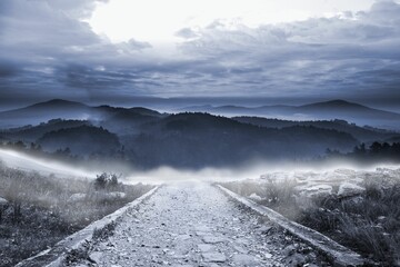 Stony path leading to large misty mountains