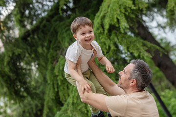 A man is holding a young boy up in the air