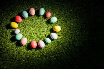 Colorful Easter eggs in circle on grass at garden © vectorfusionart