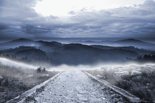 Fototapeta Stony path leading to large misty mountains