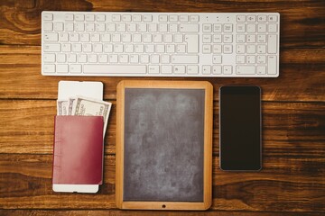 Flat top-down view showing chalkboard slate between keyboard, passport, US dollar bills, smartphone