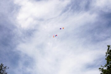 Balloons flying against cloudy sky
