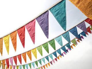 Fototapeta premium Colorful triangular pennant banners strung against a bright white sky for a festive decoration