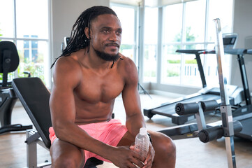 Strong muscular sport trainer sitting relax after training in gym
