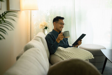Confident investor relaxing while using a digital tablet to follow the rise and fall of financial markets in real time, Tracking the Stock Market at Home