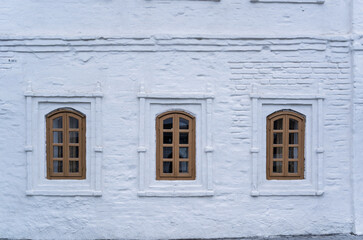 Three windows of the old 17 century building. Old stone wall with three windows