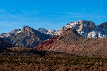 Scenic view of rugged desert mountains with snow-capped peaks under a clear blue sky in a remote...