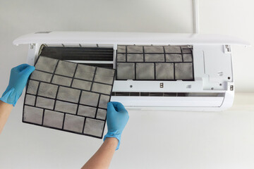 A technician's hand holds a air conditioner filter dusty. preparation for maintenance and cleaning.