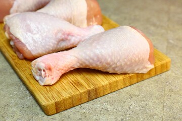 Raw chicken legs with pepper and spices on a board and plate ready for