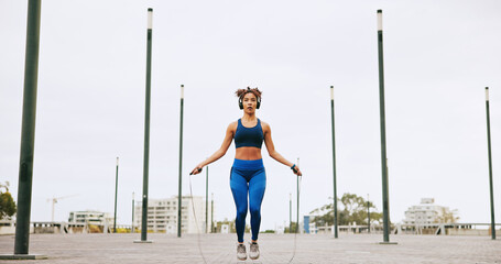 Fitness, skipping and woman in city for exercise, activity or challenge for weight loss outdoor. Sports, energy and female athlete with jump rope for cardio workout or training for health in town.