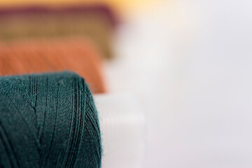 Multicolored sewing reels with threads lie on a white background. taken in close-up with space for...