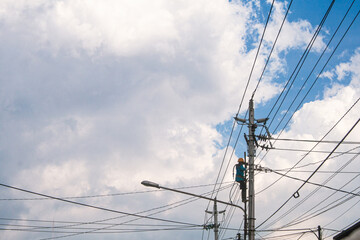 Dedicated Electrical Workers Performing Maintenance on Utility Pole Under Clear Blue Sky with Power...