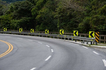 On the way up the mountain, the signaled curve warns drivers with reflective signs and vivid paint....
