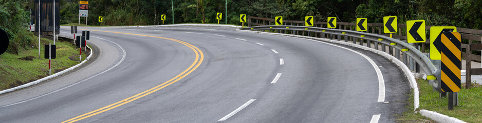 On the way up the mountain, the signaled curve warns drivers with reflective signs and vivid paint. Surrounded by fog and greenery, it demands attention and respect for nature.