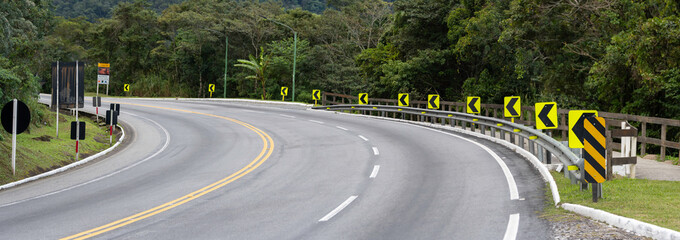 On the way up the mountain, the signaled curve warns drivers with reflective signs and vivid paint. Surrounded by fog and greenery, it demands attention and respect for nature.