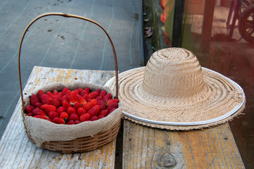 Basket and spoon hat with strawberries evoke an irresistible rural charm: red fruits, wicker and straw in harmony, harvesting sweet memories in the countryside.
