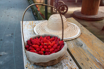 Basket and spoon hat with strawberries evoke an irresistible rural charm: red fruits, wicker and straw in harmony, harvesting sweet memories in the countryside.