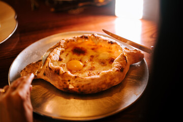 Delicious Adjarian Khachapuri served hot with melted cheese and egg at a cozy restaurant