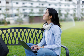 Asian female college student thinking outside with bag and book in a park, Education studying...