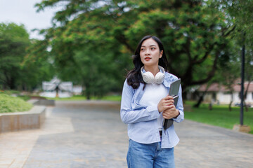 Asian woman student walking in the park chatting by mobile phone in a park, Education studying students concept
