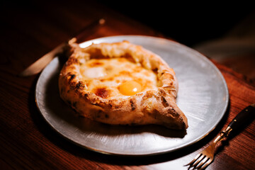 Traditional Adjarian khachapuri served on a rustic plate in a cozy setting