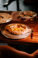 Delicious Adjarian Khachapuri served on a metallic plate in a cozy dining setting