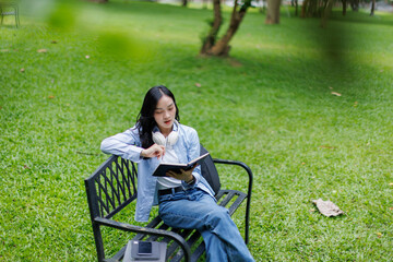 Fototapeta premium Autumn portrait of a beautiful happy asian woman college student reading book in park.Education studying students concept 