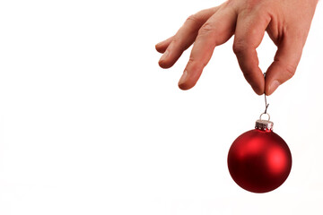 Hand holding red Christmas tree ornament on white background