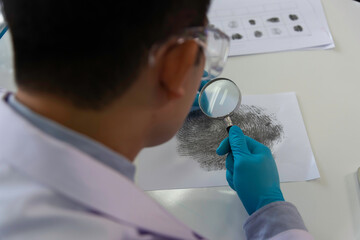 Forensic fingerprint analysis, criminalist collects latent fingerprints using fingerprint powder on...