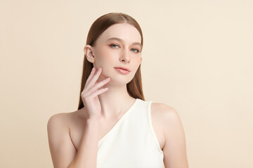 A beautiful young woman with clean, fresh skin against a beige background. Skincare, facial...