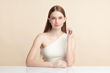 A beautiful young woman with clean, fresh skin against a beige background. Skincare, facial...
