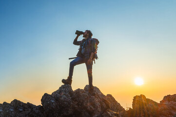 man is standing on a mountain top, looking through a camera lens