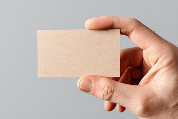 Hand holding a blank, light brown business card. High quality